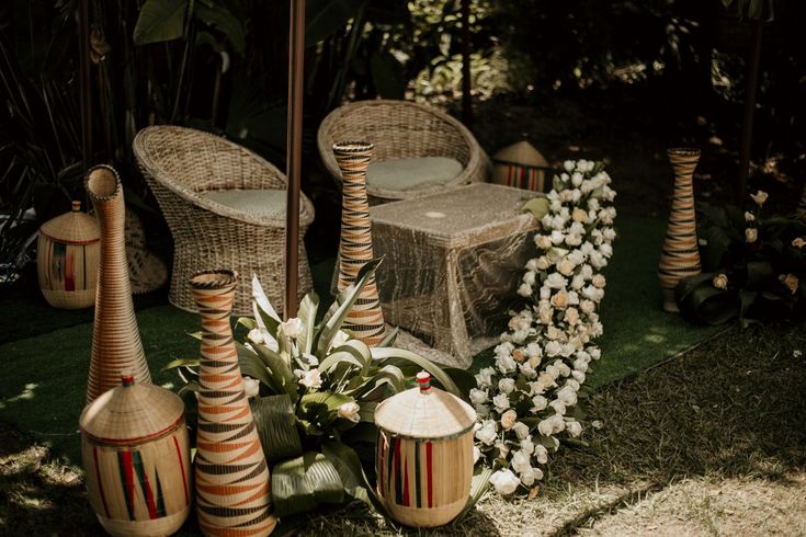 an arrangement of vases and chairs on the ground in front of some trees with white flowers