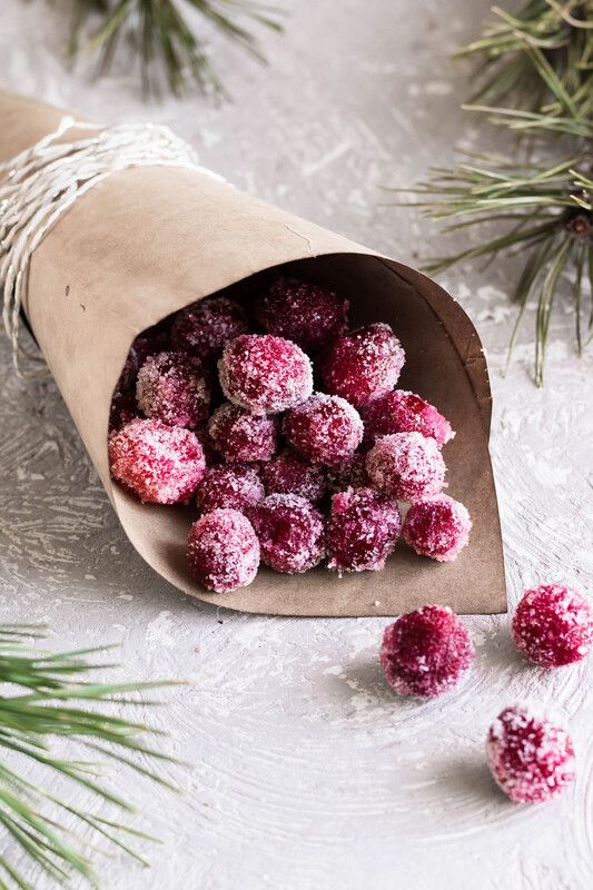 a bag filled with powdered sugar next to pine needles and snow flakes on a white surface