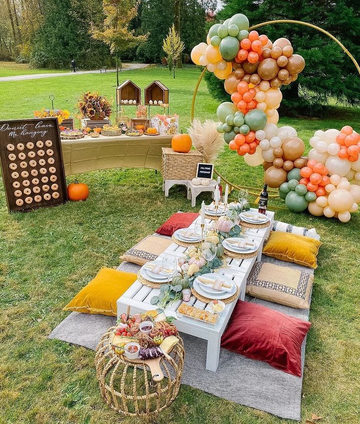 an outdoor table set up for a party with balloons and plates on the table, along with other decorations