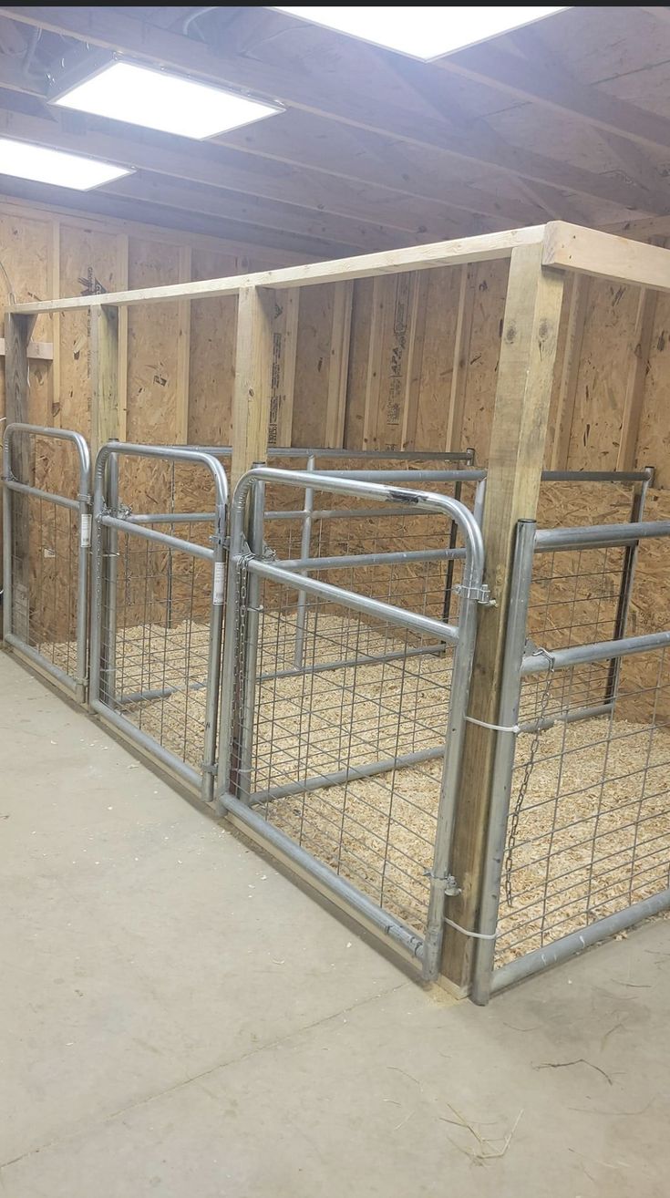 the inside of a barn with metal bars and hay bales on the floor in front of it