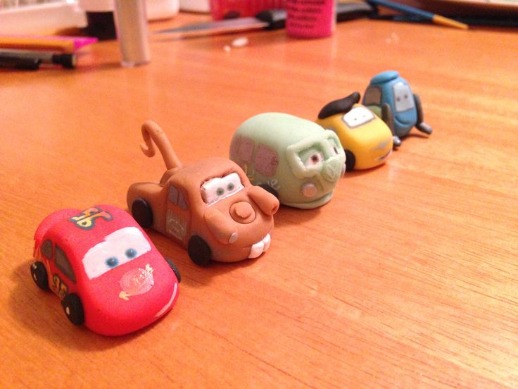 three toy cars are lined up on the table next to each other, one has a face