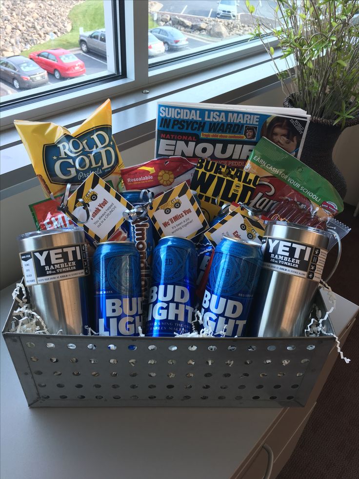 a metal basket filled with lots of different types of drinks and snacks next to a window