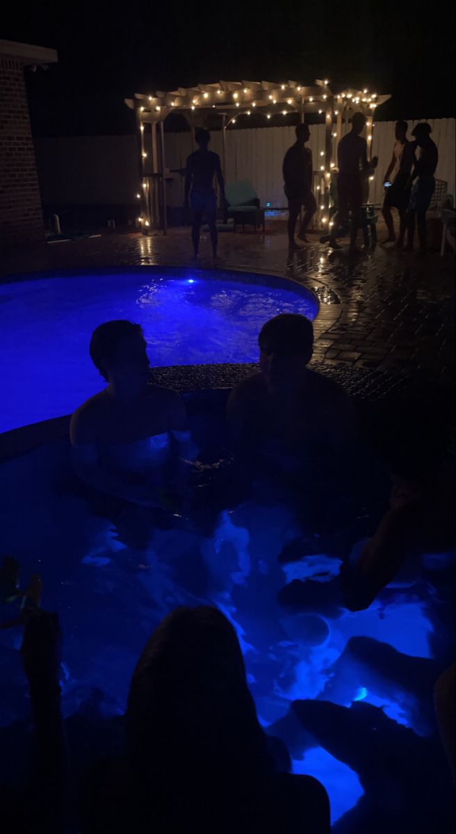 people are sitting in the pool at night