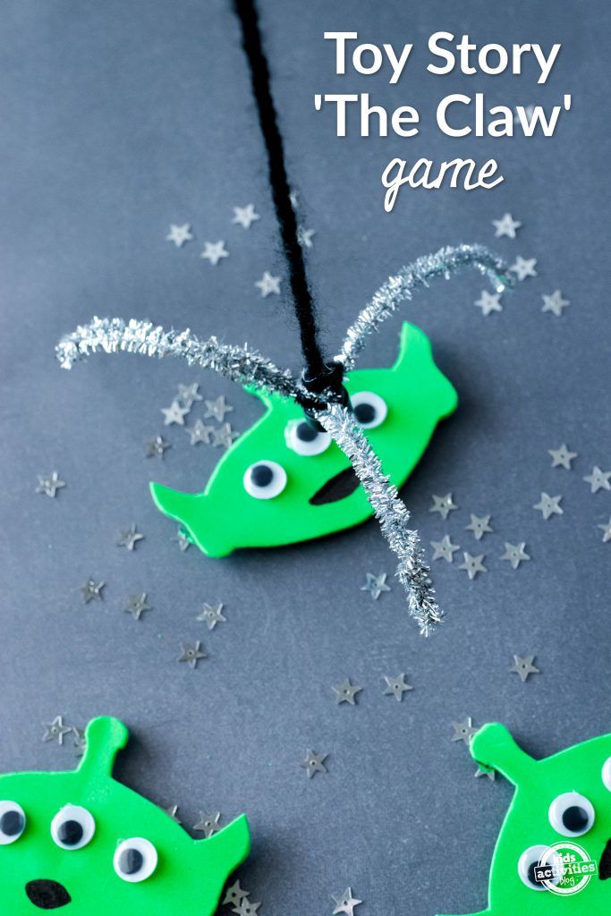 two green necklaces with googly eyes and stars around them on a gray surface