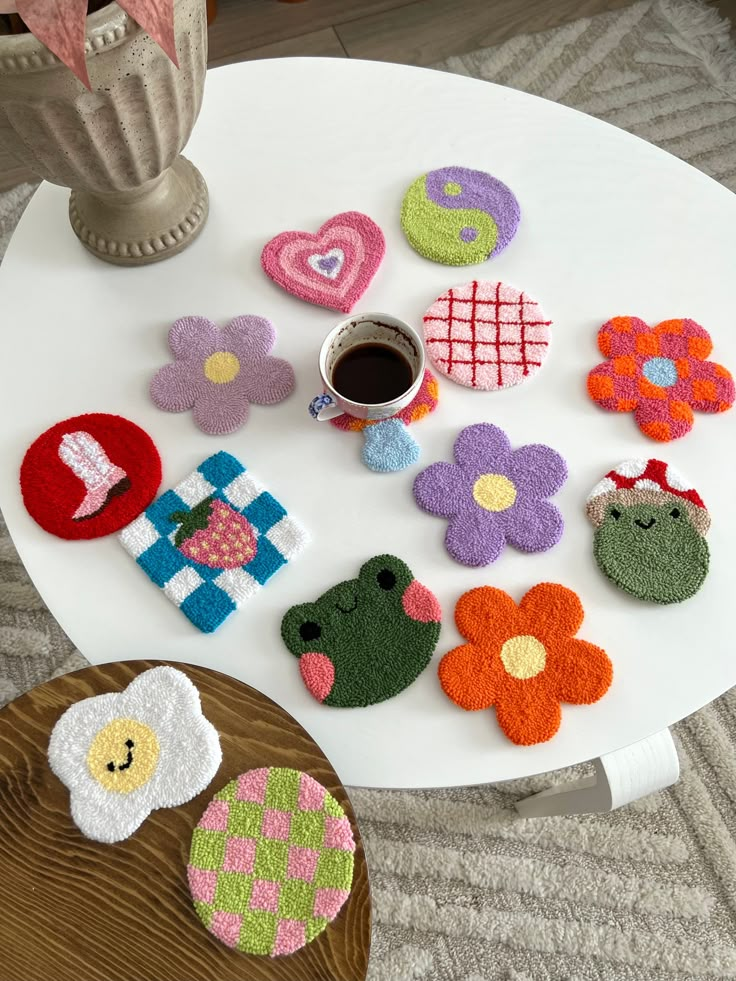 there are several felt flowers on the table next to a cup of coffee and a vase