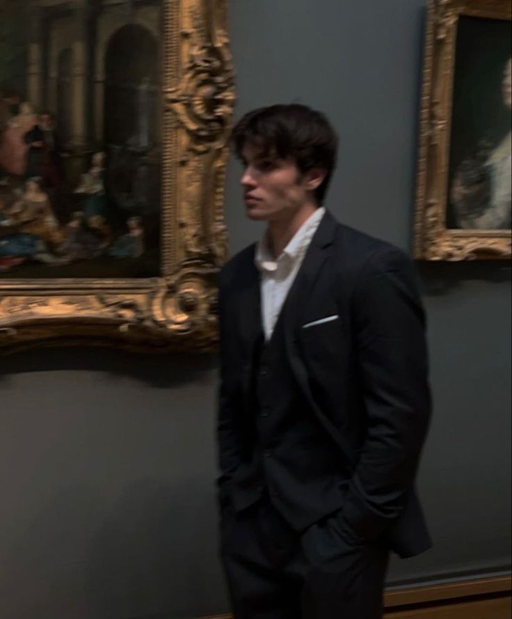 a man in a suit standing next to a painting