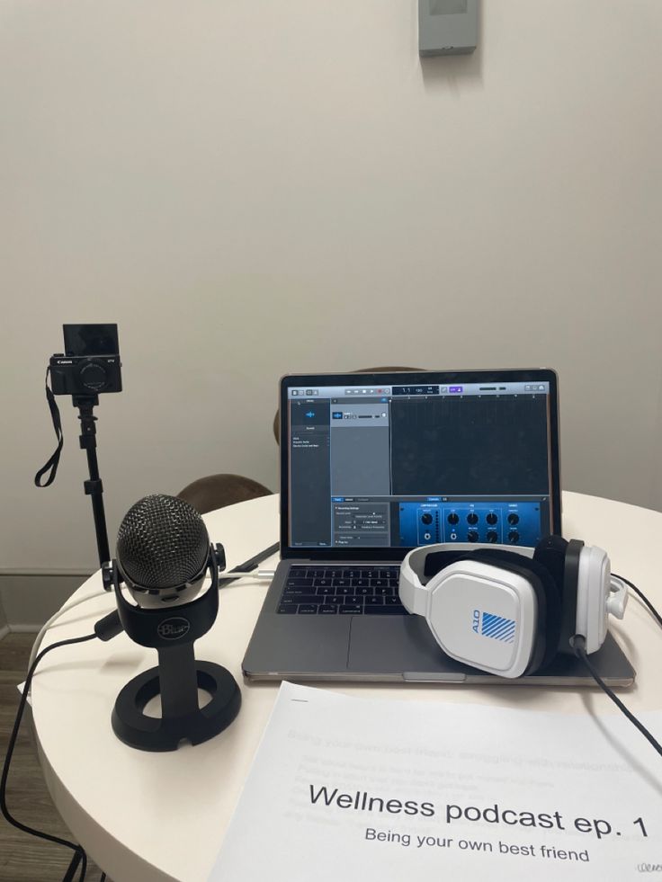 an open laptop computer sitting on top of a table next to a microphone and headphones