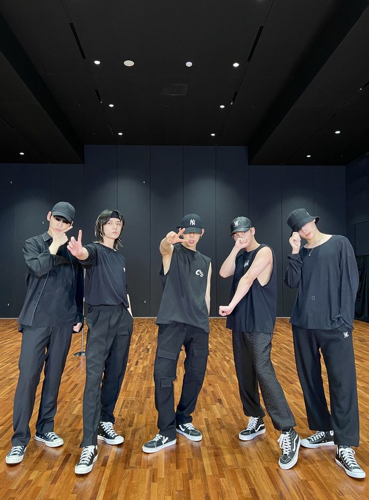 five young men standing on top of a wooden floor