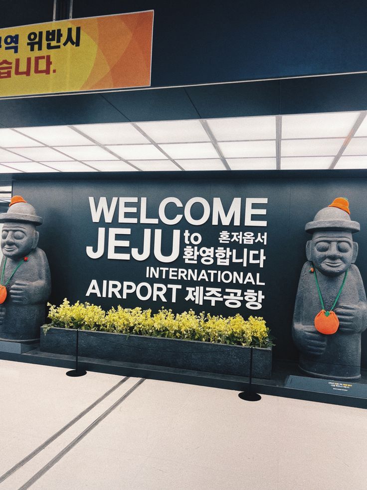 a welcome sign for jeju international airport in south korea, with two statues holding carrots