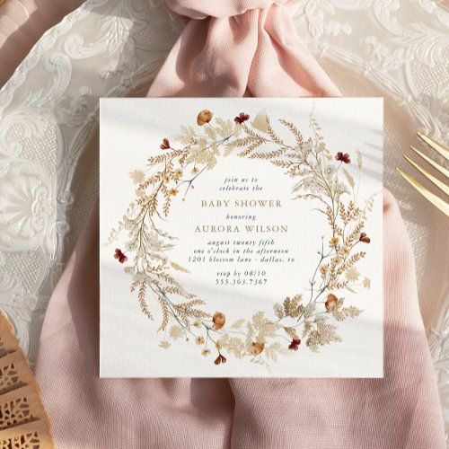 a white and gold wedding card on top of a pink napkin next to a fork