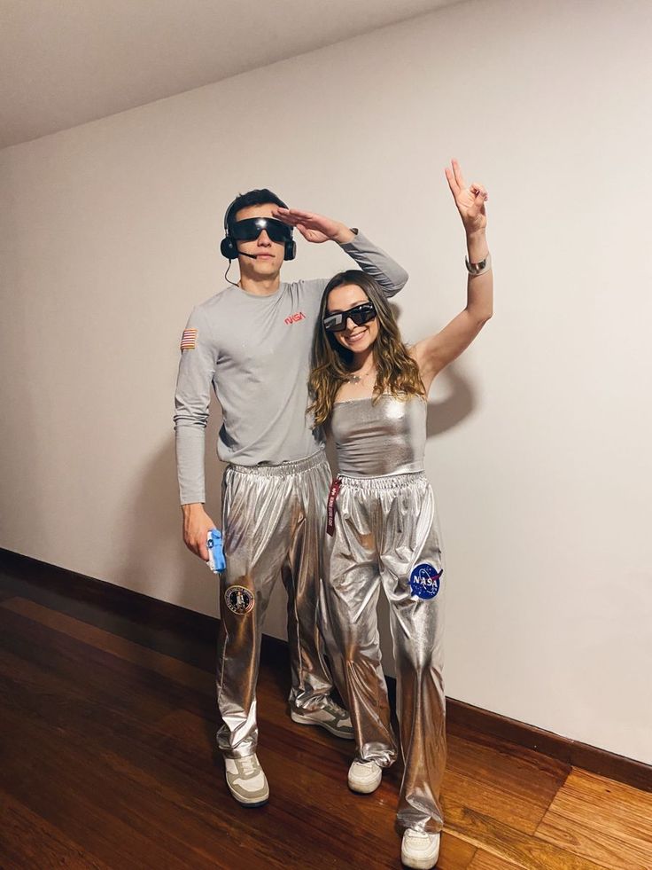 a man and woman dressed in silver posing for a photo with their hands up to the camera