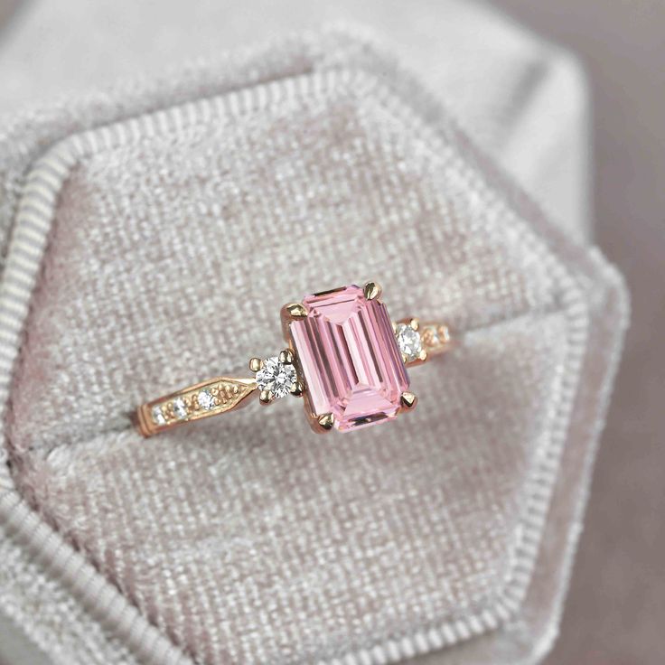 a pink tourmaline and diamond ring sitting on top of a white cloth bag