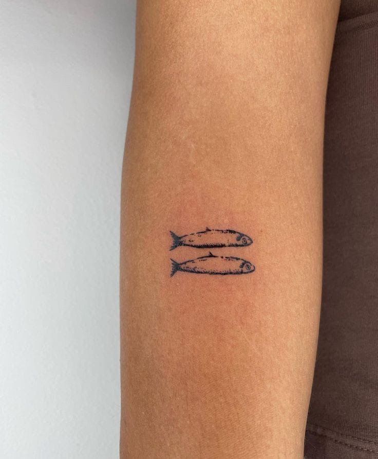 a woman's arm with two fish tattoos on the left side of her body