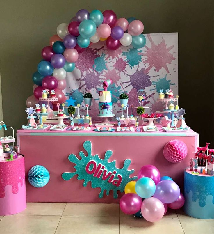 a table topped with lots of balloons next to a pink and blue counter top filled with candy