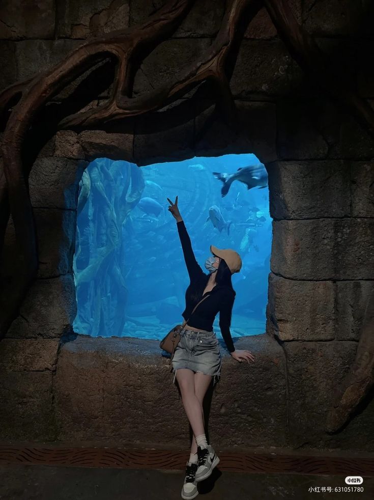 a woman standing in front of an aquarium window