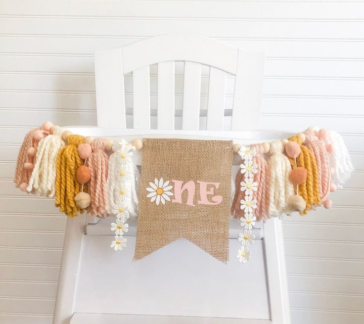 a white chair with a burlap banner and flowers on the back of it