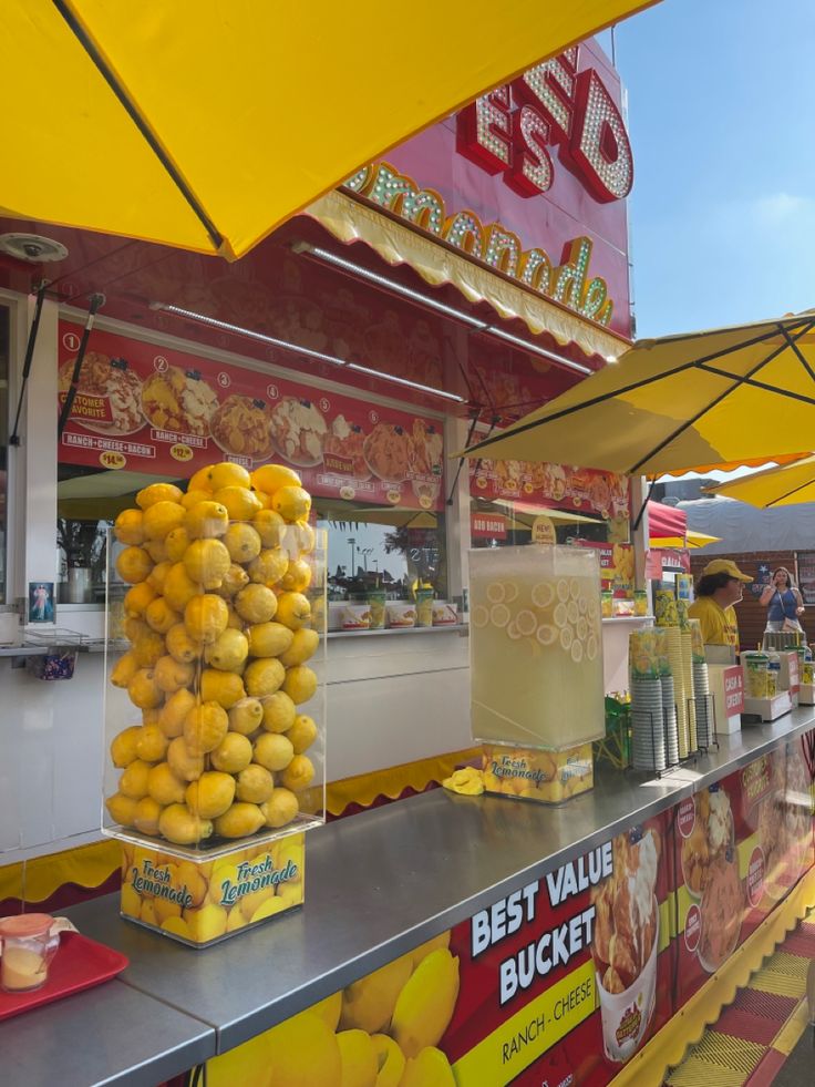 lemons and other fruit are on display at a food stand with yellow umbrellas