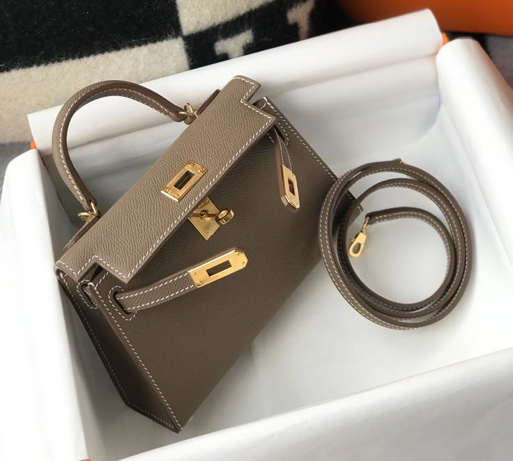 Description HRMS Greige Togo Brown With Gold Toned Hardware Bag For Women, Handbags, Shoulder Bags 7.5in/19cm Rep 1:1 Size: 19 x 11.5 x 5.5 cm / 7.5 x 4.5 x 2.2 inches (Length x Height x Width) Hermès bags are considered the ultimate luxury item worldwide. Each piece is handcrafted with waitlists that can exceed a year or more. The streamlined and demure Kelly style is always in high demand, it is particularly lovely in this vibrant version with gold hardware. Epsom is textured with a wonderful Mini Kelly, Kelly Bag, Fancy Bags, Hermes Handbags, Hermes Bags, Cute Bags, Leather Messenger, Hermes Bag, Bag For Women