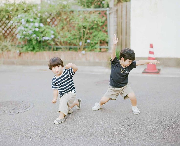 two young boys are playing in the street