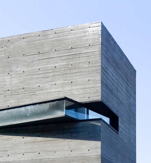 a tall building with a window on the top of it's side and sky in the background