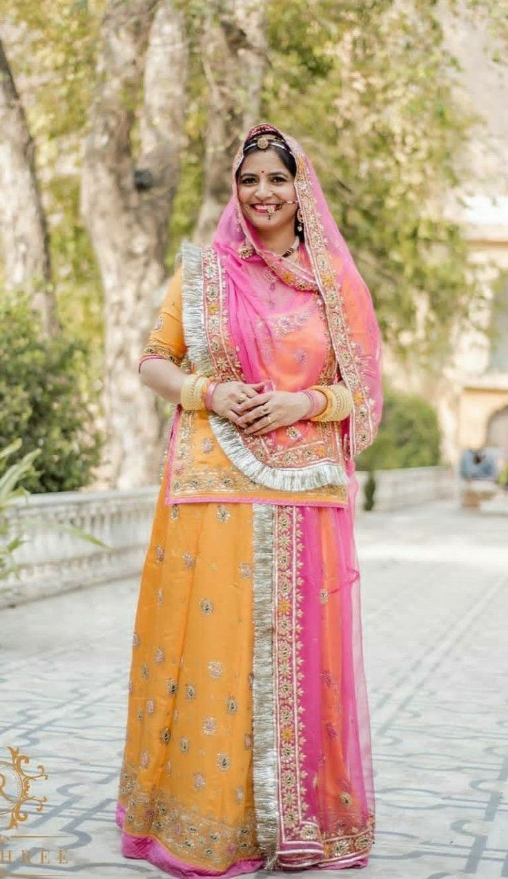 a woman in an orange and pink outfit posing for the camera with her hands on her hips