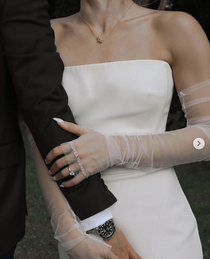 a woman in a white dress is holding the arm of a man wearing a tuxedo