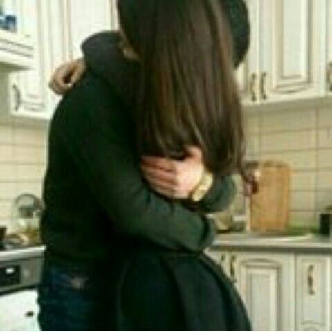 two people hugging in a kitchen with white cabinets