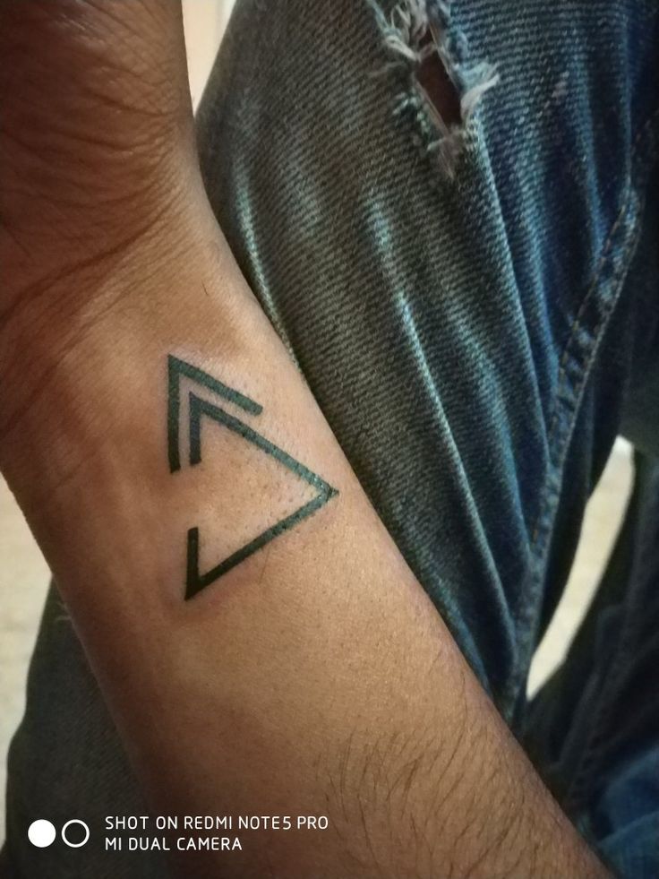 a man with a small triangle tattoo on his arm