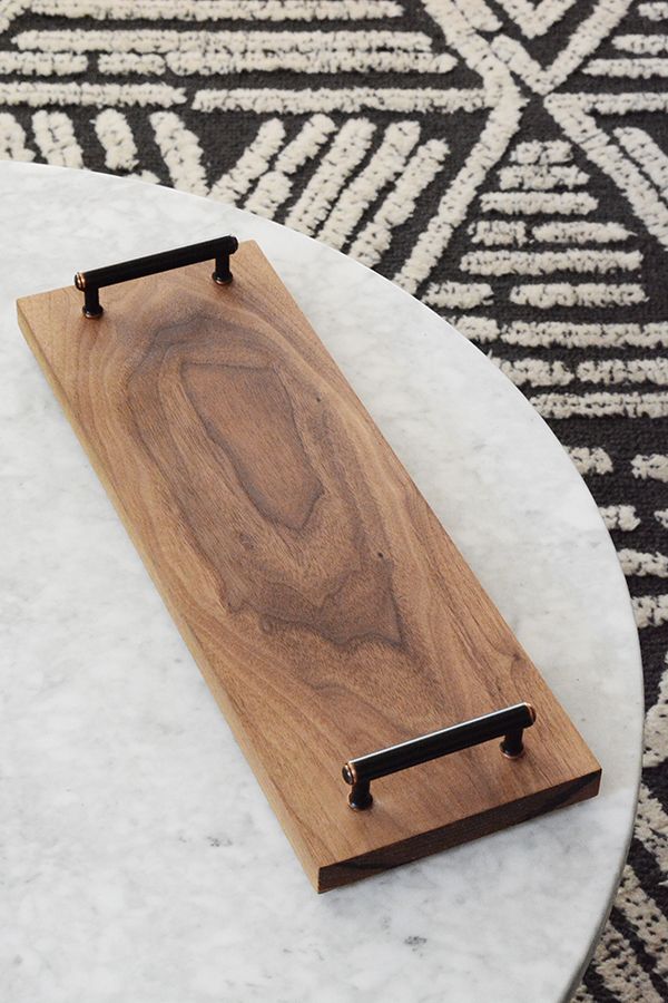 a wooden board sitting on top of a white table next to a black and white rug