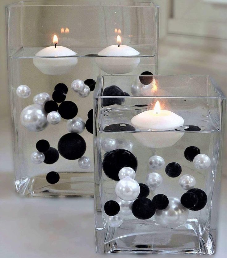 two clear vases with black and white balls in them, one filled with candles