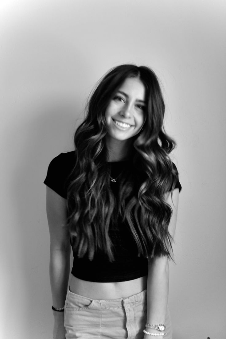 black and white photograph of a smiling woman with long dark hair, wearing a short skirt