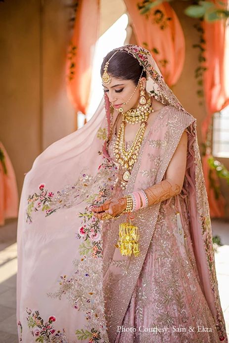 a woman in a pink lehenga with gold jewelry on her neck and hands