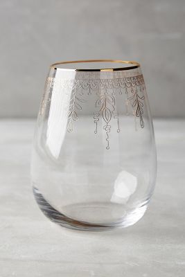 a clear glass with an intricate design on the bottom and gold trim around the rim