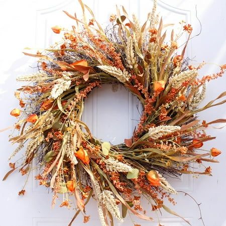 a wreath is hanging on the door with dried flowers and leaves in it's center