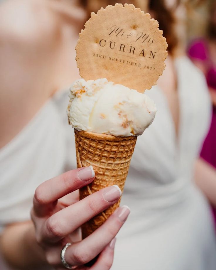 a woman holding an ice cream cone with a sign on it