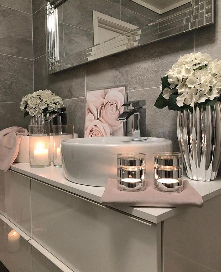 a bathroom vanity with candles and flowers on it