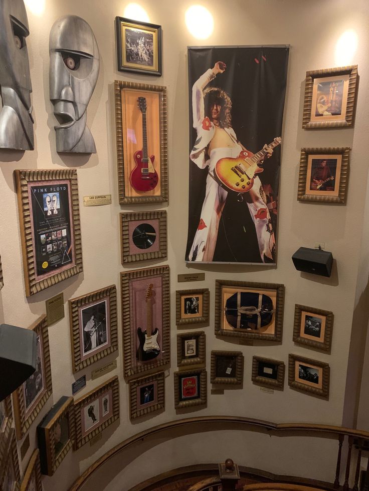 a wall with many framed pictures and guitars on it's sides, including a guitar