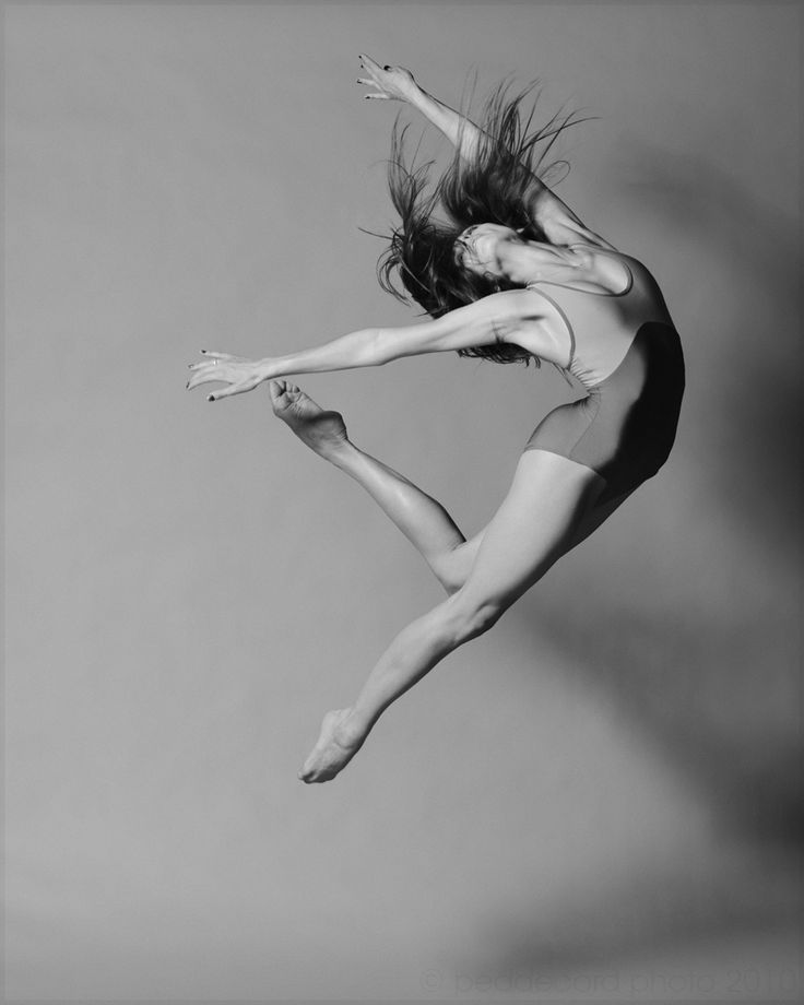 a black and white photo of a woman jumping in the air