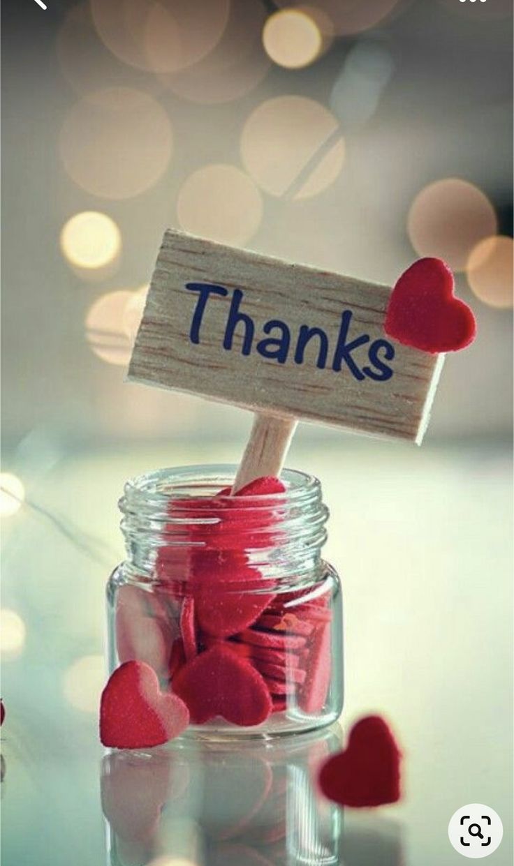 a jar filled with lots of hearts sitting on top of a table next to a sign that says thanks