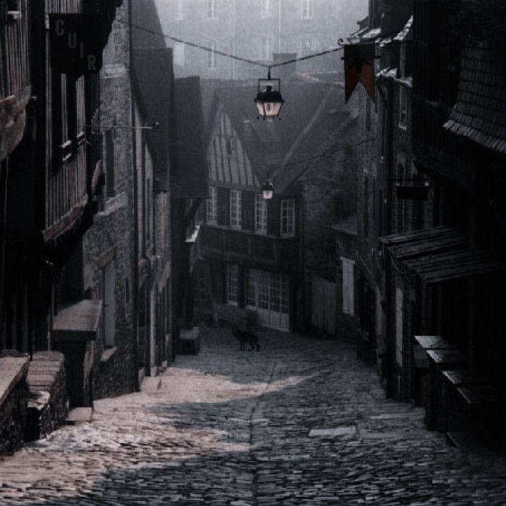 an alleyway with cobblestone streets and buildings in the background on a foggy day