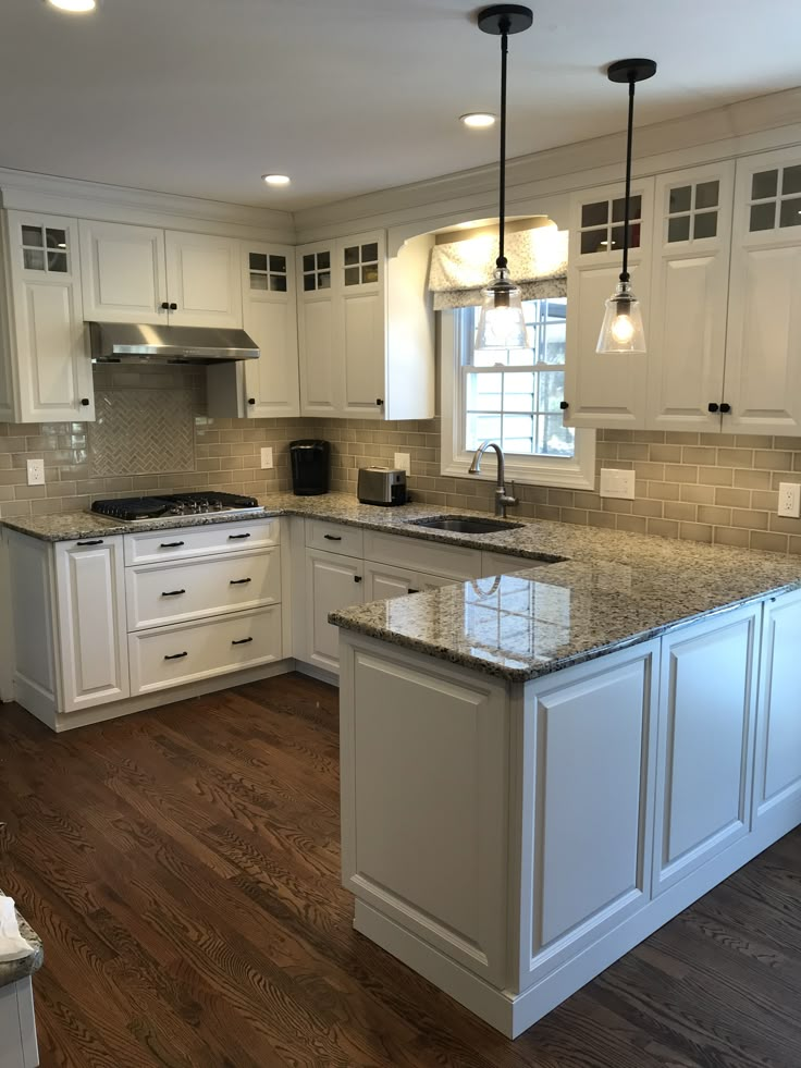 a large kitchen with white cabinets and granite counter tops on the island in front of the sink