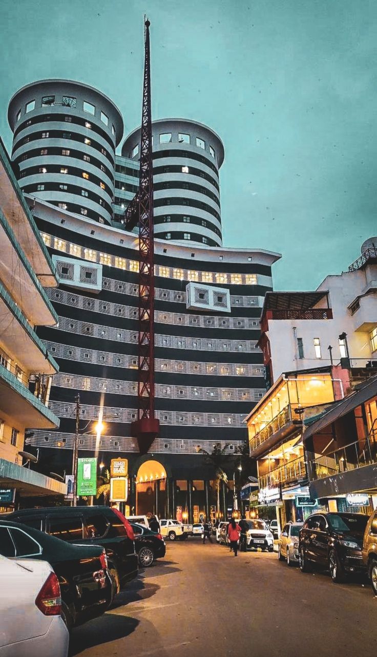 a very tall building sitting in the middle of a street with cars parked around it