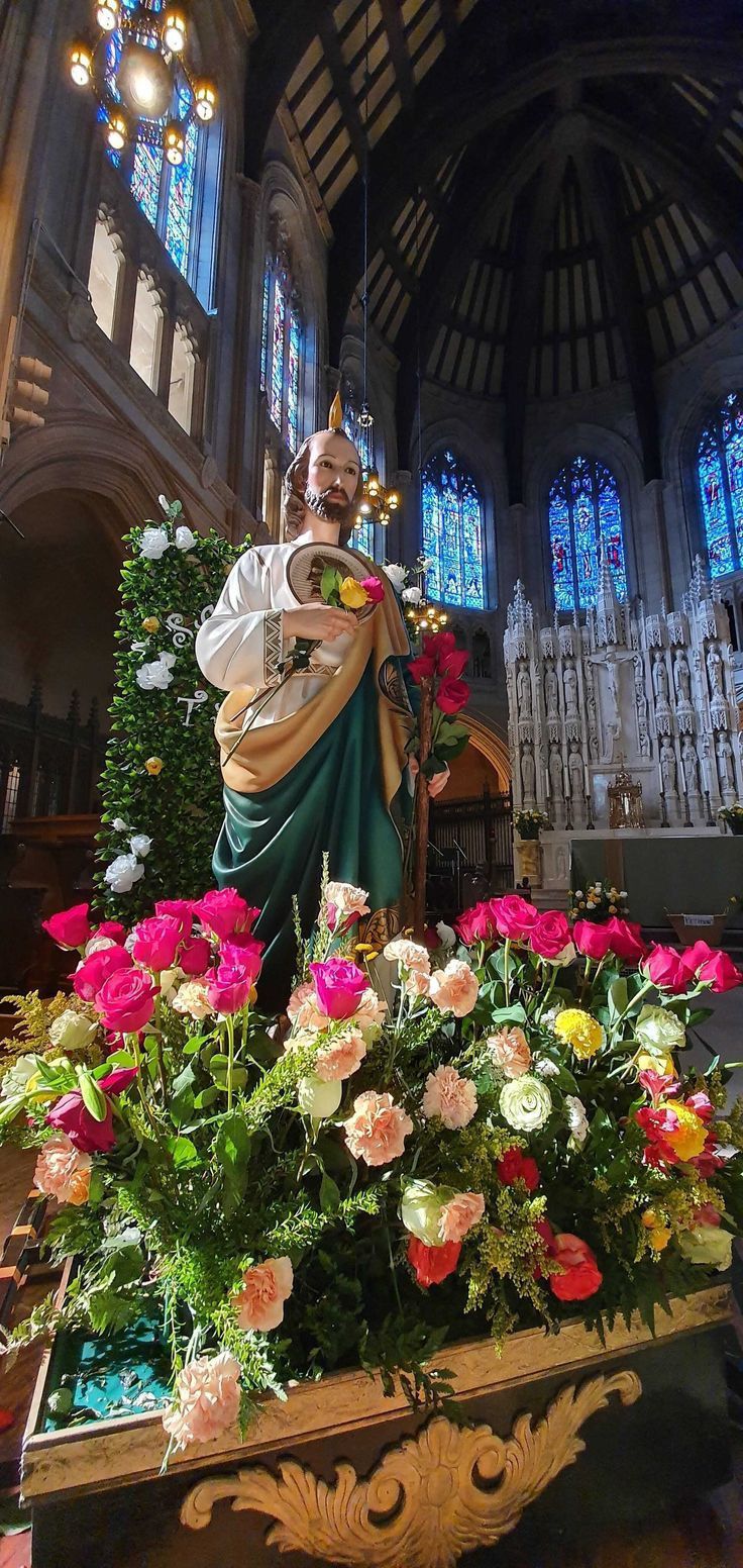 a statue of the virgin mary in front of flowers and stained glass windows at st patrick's cathedral