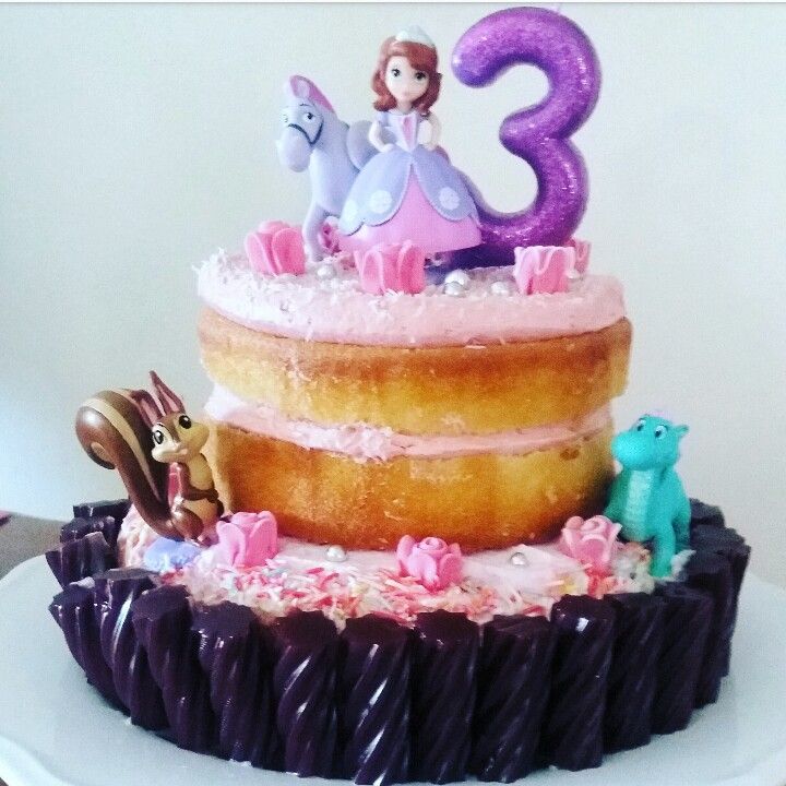 a three tiered birthday cake with princess and prince figures on top, sitting on a plate