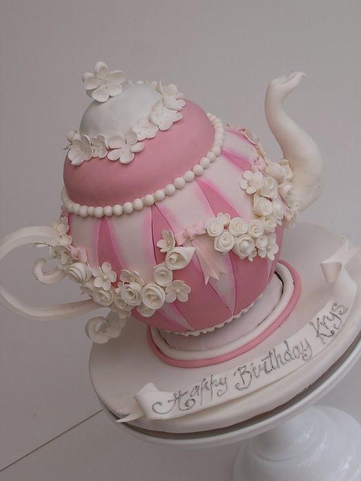 a pink and white teapot cake with flowers on top