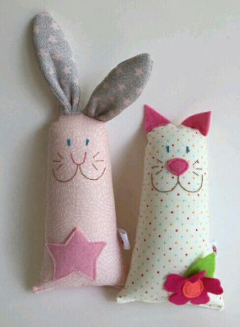 two stuffed animals sitting next to each other on top of a white surface with pink and gray polka dots