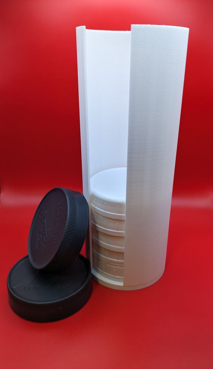 a stack of plates and a plastic cup on a red surface with a black lid