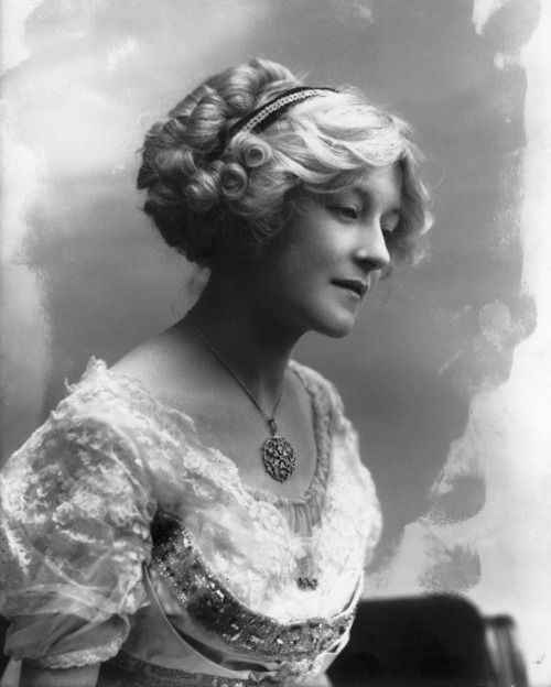 an old black and white photo of a woman in a dress with a necklace on her neck