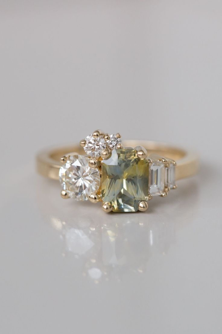 an engagement ring with three stones on the side and one stone in the middle, sitting on a white surface