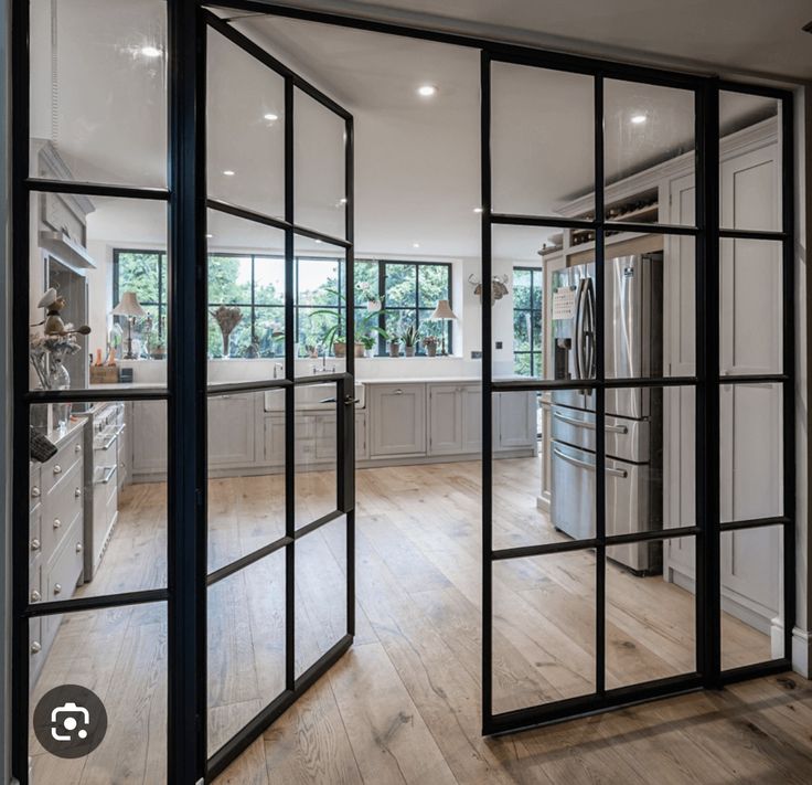 an open kitchen with glass doors leading to the dining room and living room, as well as large windows